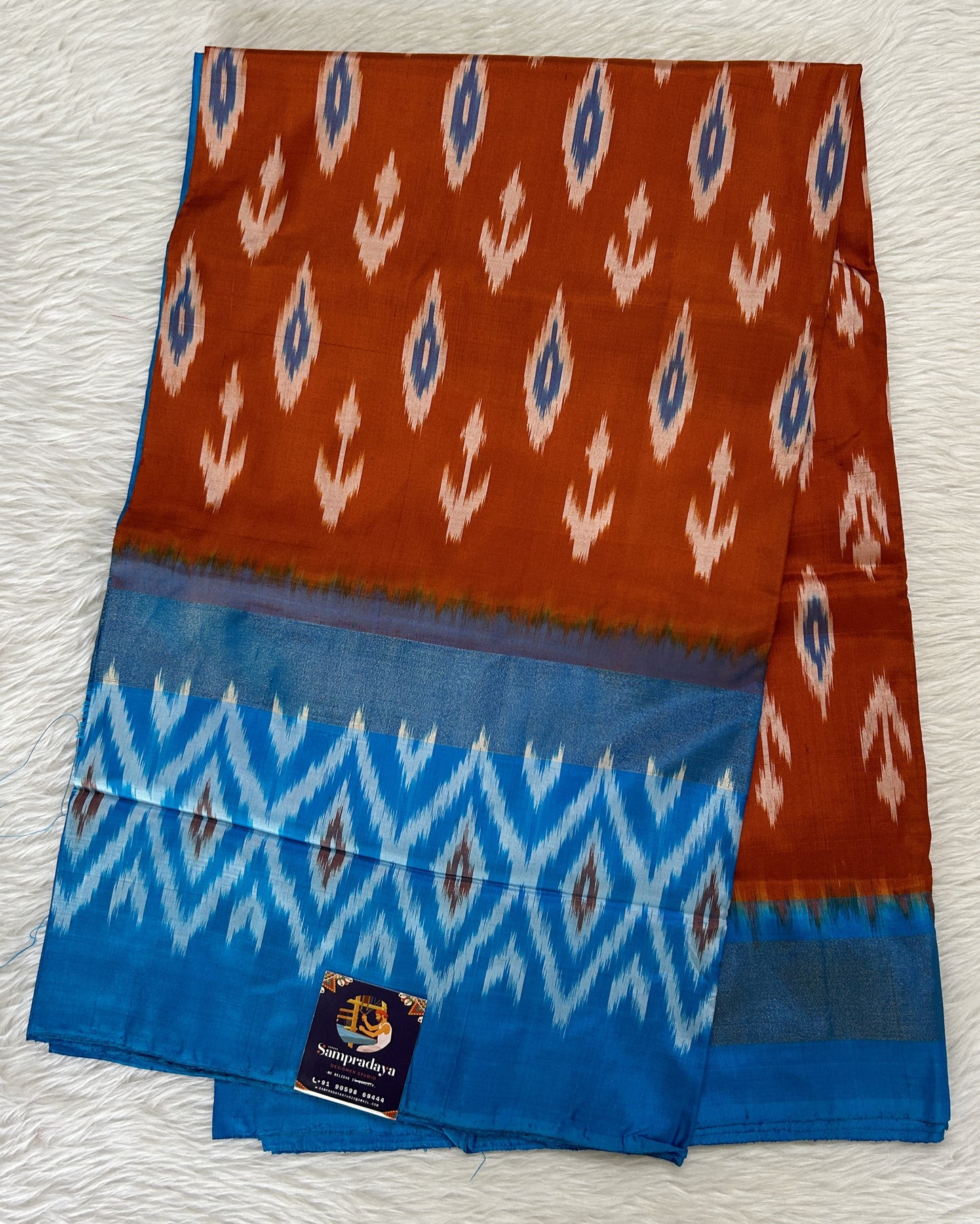 Ikkat Pattu Saree Rust Orange colored Saree complemented with a Blue Colored Ikkat border. - Sampradaya Designer Studio