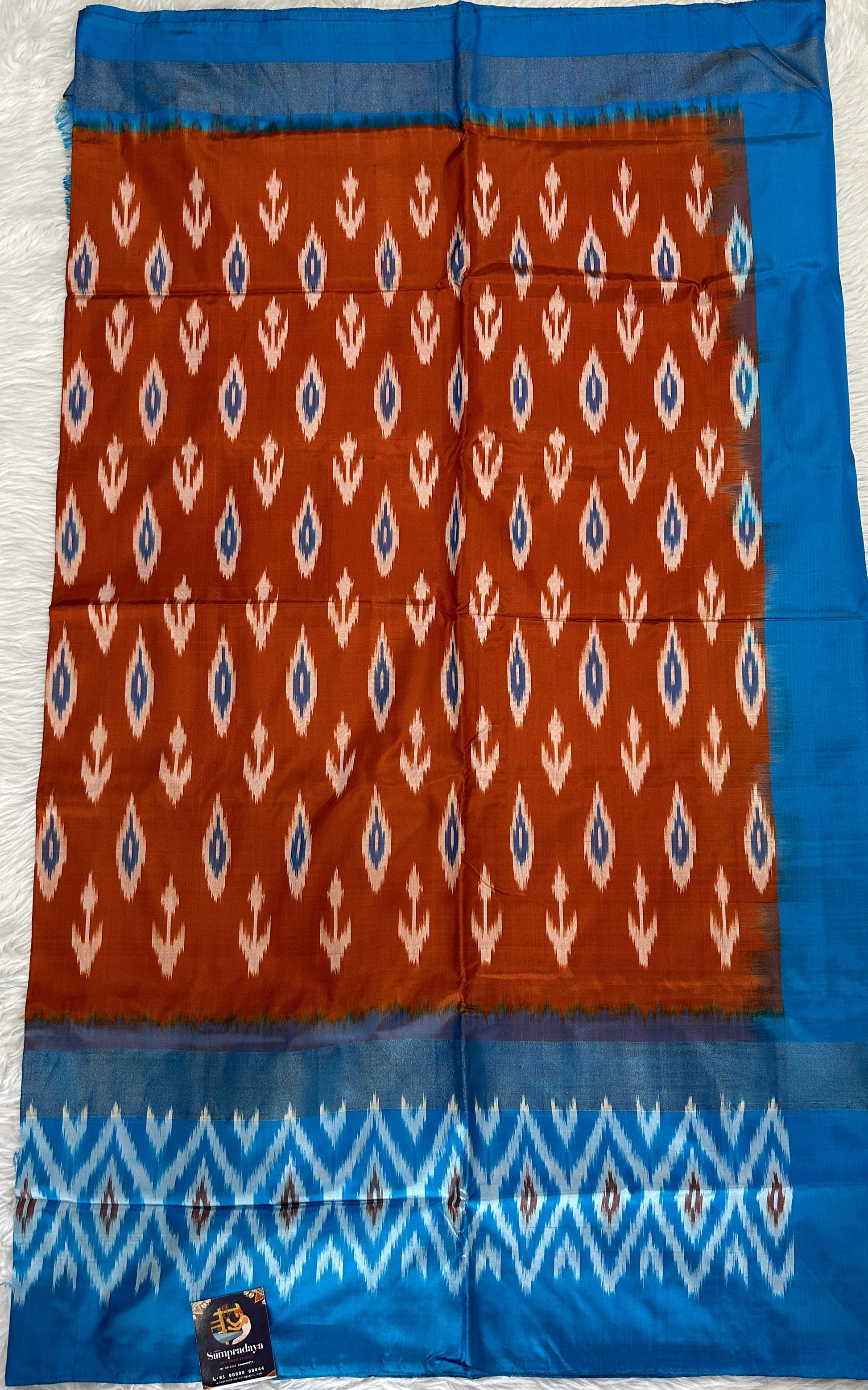 Ikkat Pattu Saree Rust Orange colored Saree complemented with a Blue Colored Ikkat border. - Sampradaya Designer Studio