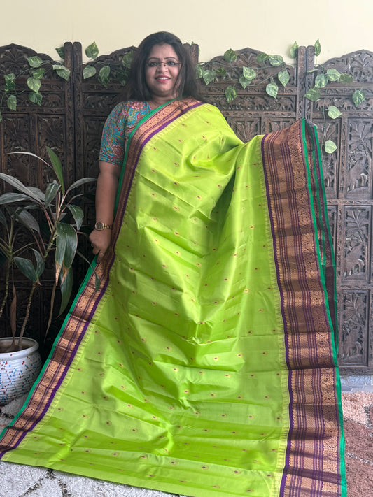 Gadwal Pattu Saree Parrot Green colored saree complemented with a Purple Zari border