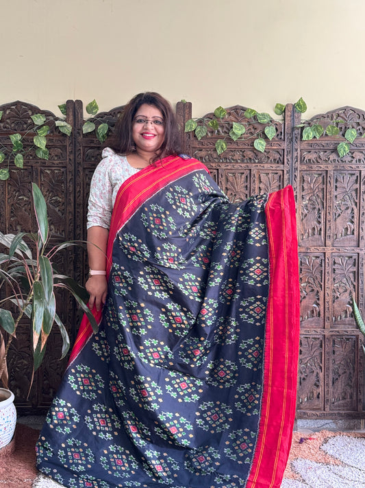 Ikkat Pattu Saree Black colored complemented with a Red Patola border.