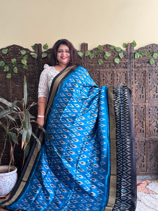 Ikkat Pattu Saree Sky Blue colored complemented with a Black Patola border.