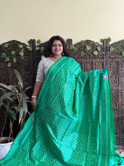 Ikkat Pattu Saree Parrot Green colored complemented with a Patola border.